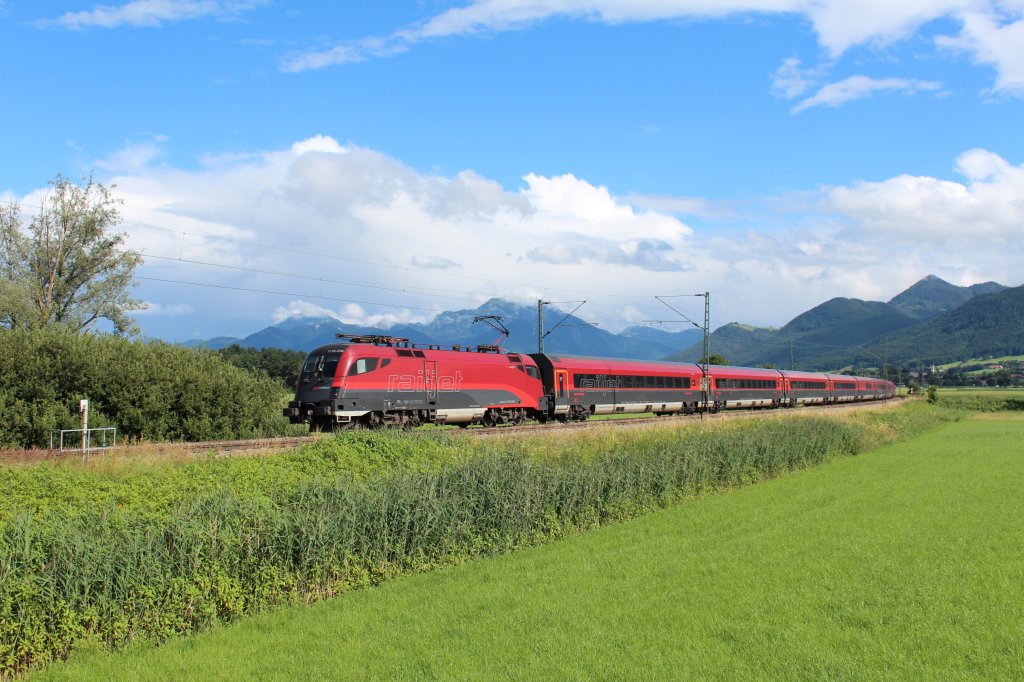 Von Salzburg kommend fotografierten wir diesen  Railjet  zwischen Bernau und Prien am Chiemsee am 15. Juli 2012. Im Hintergrund die Wolken verhangenen Hochgern und Hochfelln.