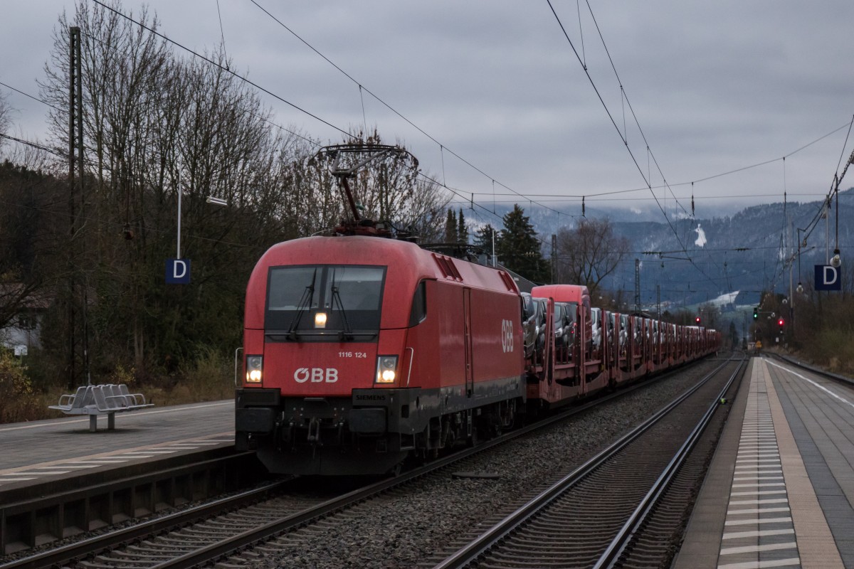 1116 124 durchfhrt am 28. November 2015 mit einem Autozug aus Salzburg kommend den Bahnhof von Prien am Chiemsee.