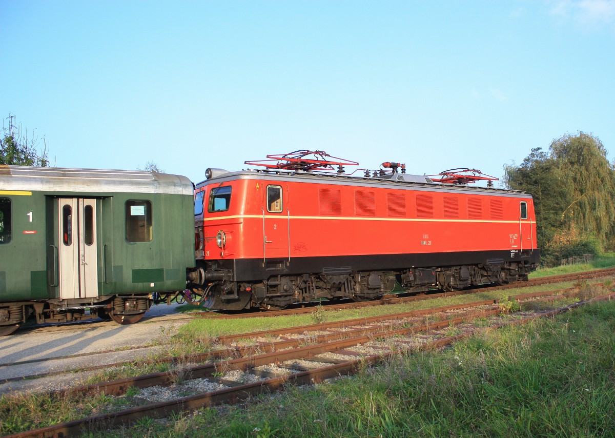 1141.21 befand sich am 4. Oktober 2014, am Zugende eines Sonderzuges der soeben den Bahnhof von Timmelkam in Richtung Ampflwang verläßt.