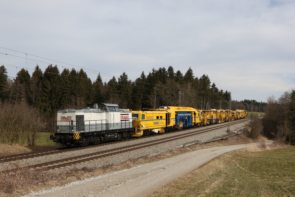 V 100 der Firma  STRABAG  mit einem Bauzug von  KREBS Gleisbau  am 3. Mrz 2021 bei Grabensttt im Chiemgau.