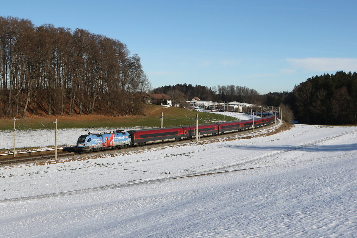 1116 233  Saalbach  schiebt am 16. Januar 2026 einen  Railjet  bei Axdorf im Chiemgau in Richtung Salzburg.